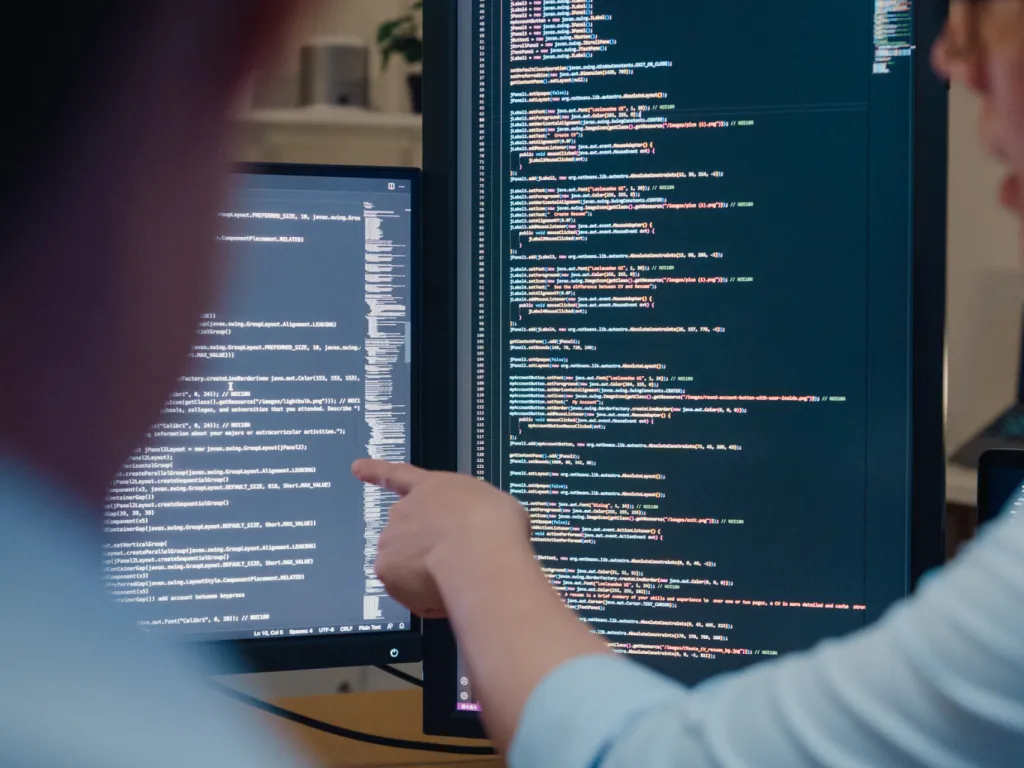Man pointing to computer screen with code